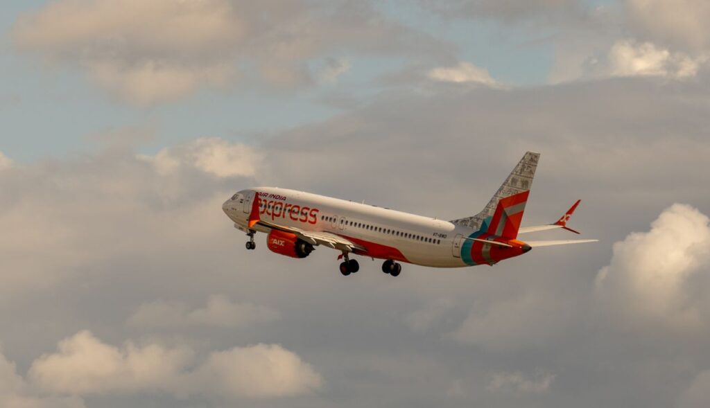 Air India Express aircraft soaring into the sky with a backdrop of clouds, symbolizing travel and adventure.