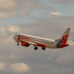 Home Air India Express aircraft soaring into the sky with a backdrop of clouds, symbolizing travel and adventure.