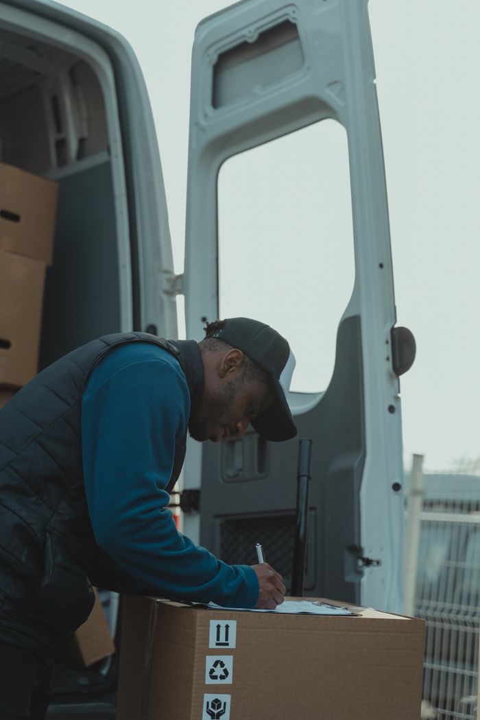 Crafting Captivating Headlines: Your awesome post title goes here A delivery worker signs documents outside a parked van, managing logistics efficiently.